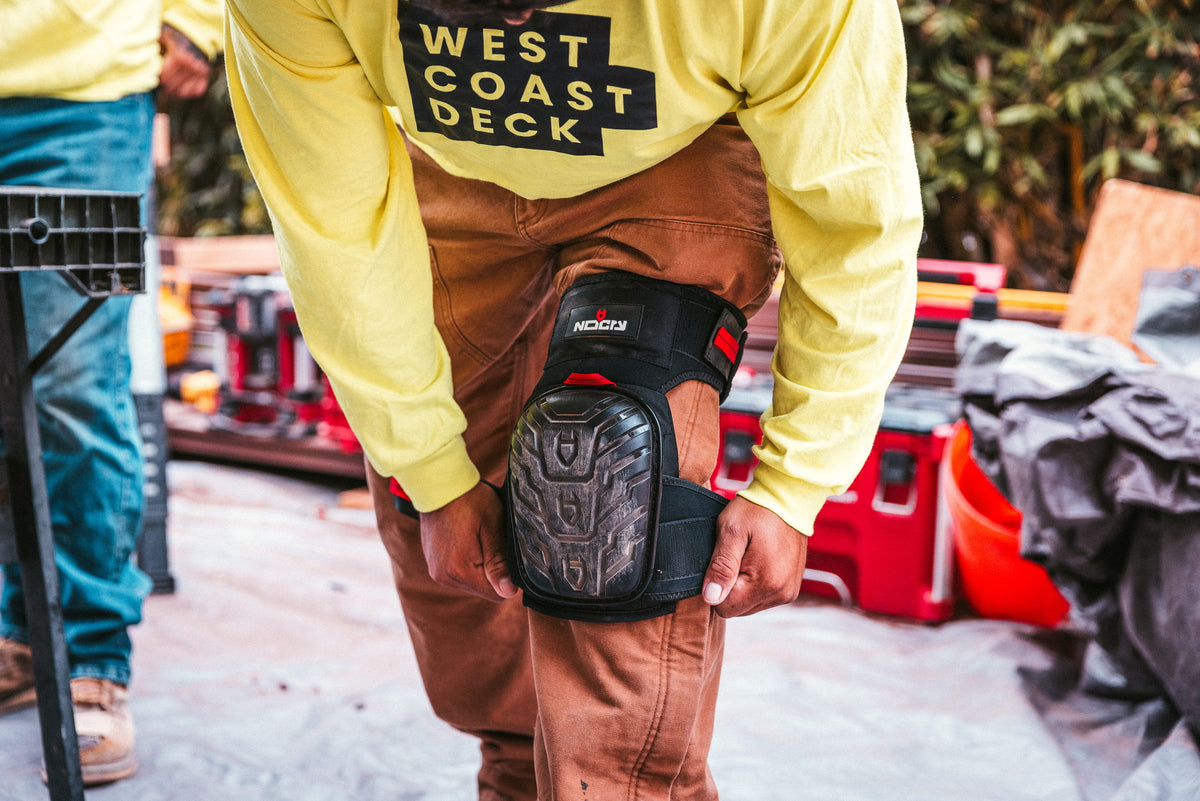 [First name], tile setter, adjusting the thigh strap on the leg, buckle and strap length visible, work pants, head in frame. Callout: "adjustable both sides".